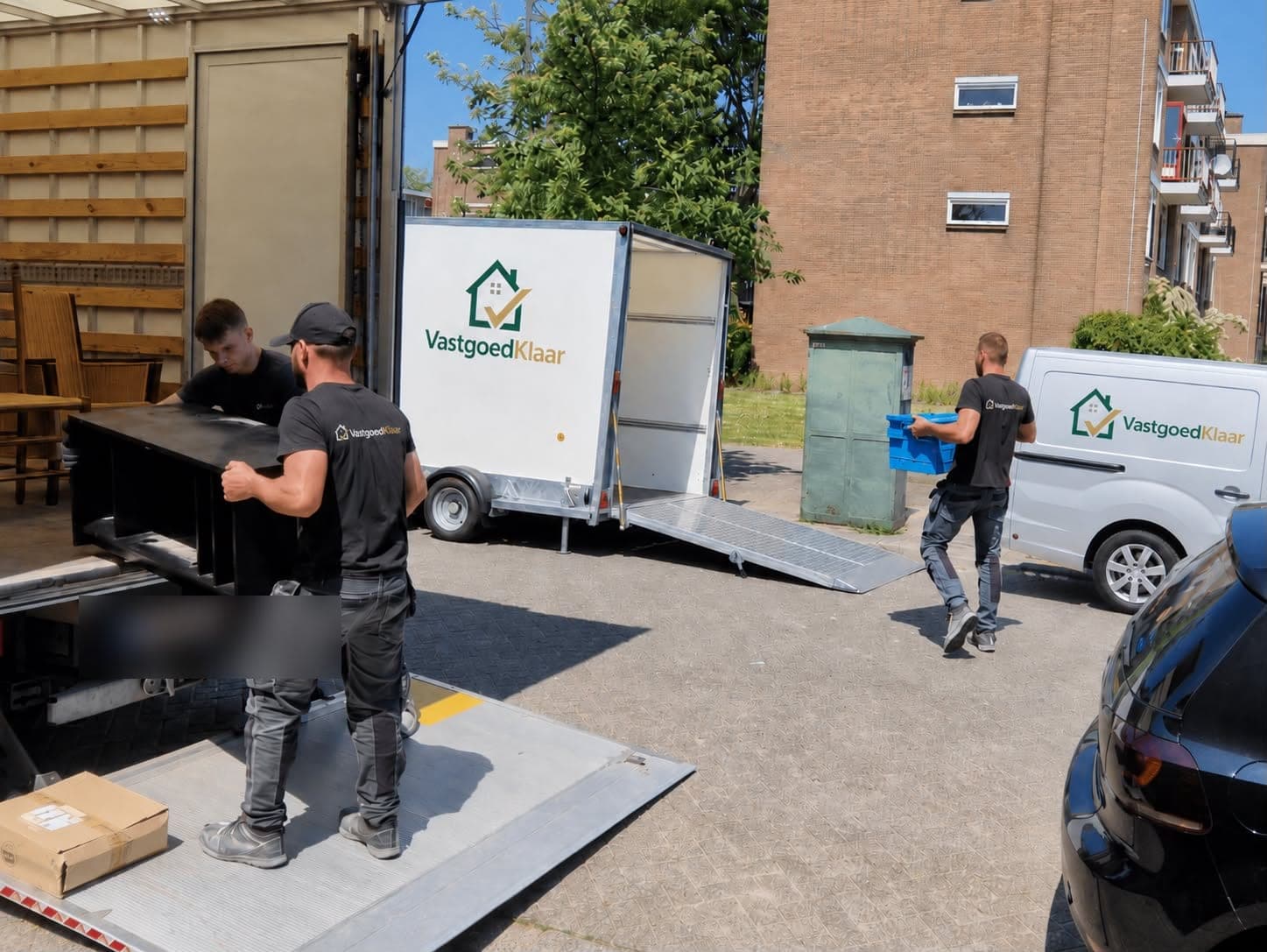 Het team van VastgoedKlaar laadt meubels in de bestelwagen en aanhanger tijdens een woningontruiming